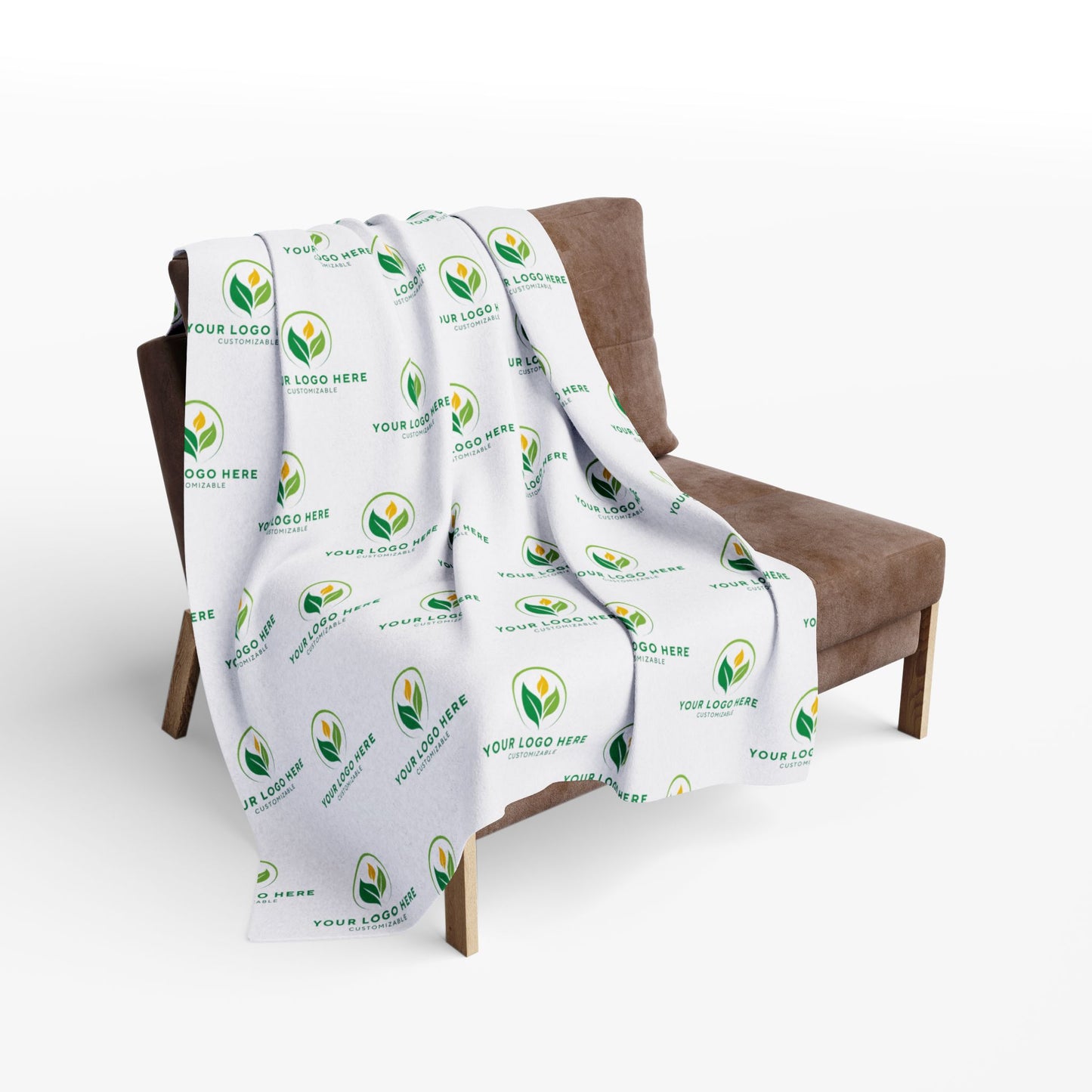 White blanket with green leaf logo draped over a brown chair on a white background