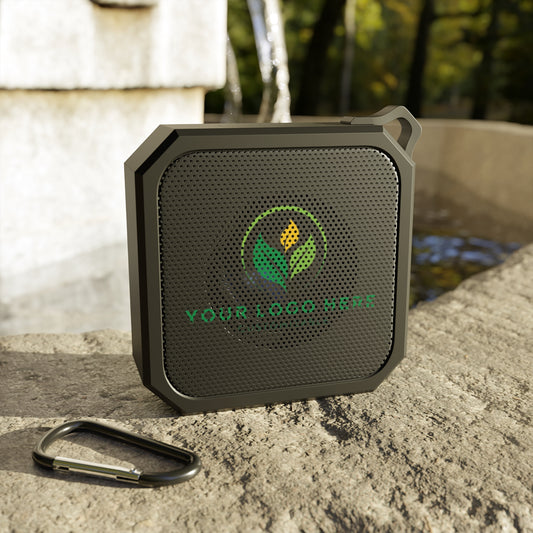 Black portable speaker with a logo on a stone surface