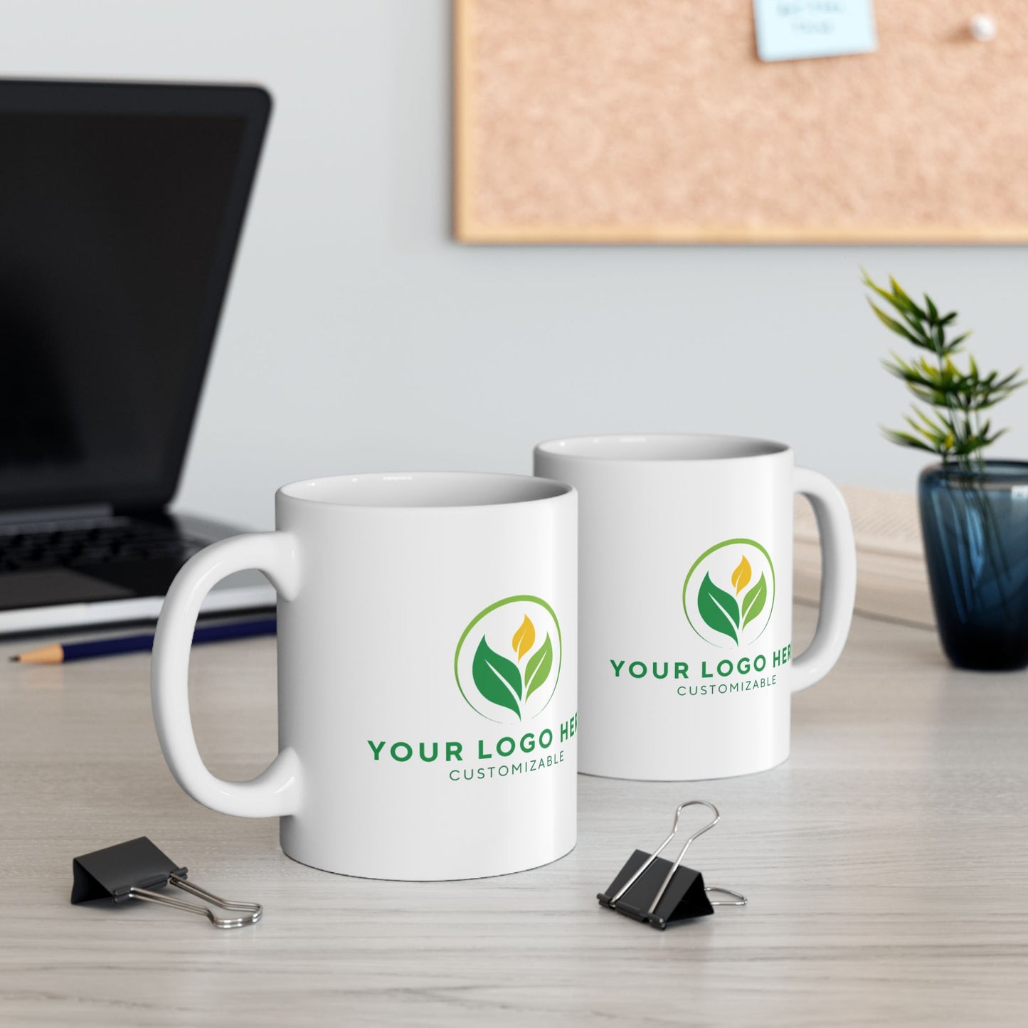 Two white mugs with a logo on a desk with office supplies.