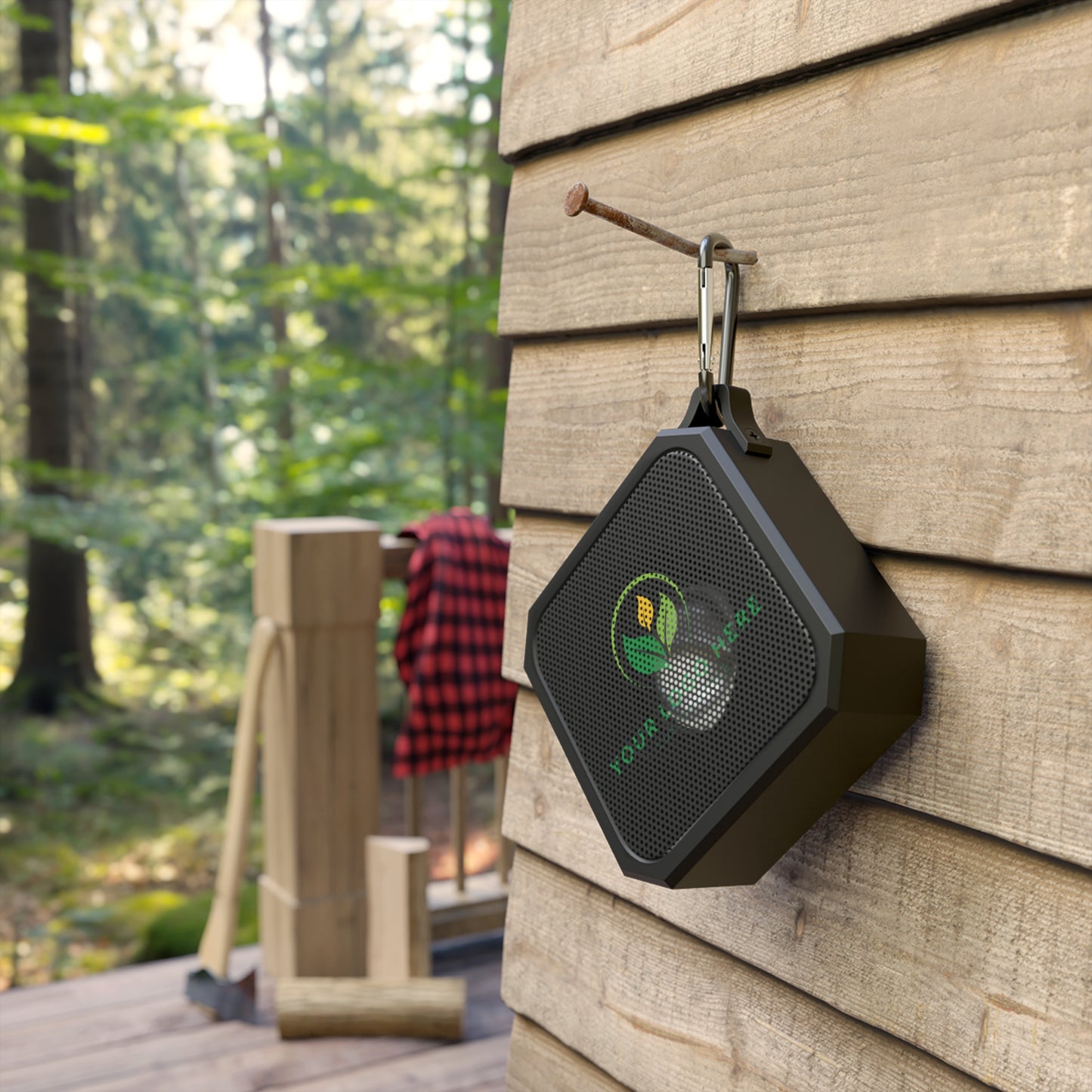 Black outdoor speaker with a logo attached to a wooden wall outdoors.