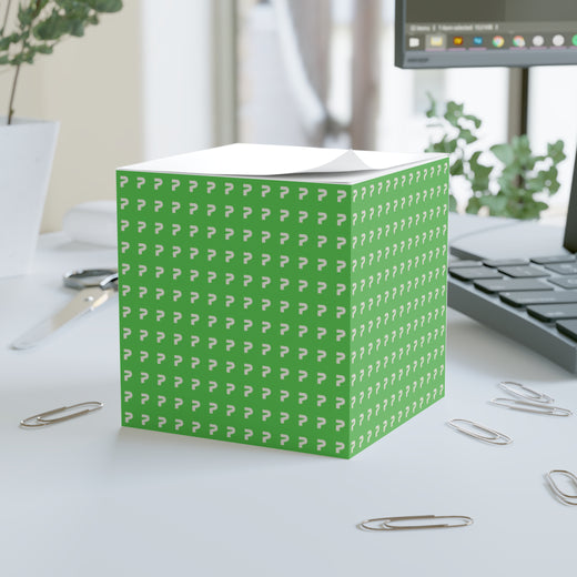 Green cube with white pattern on a desk with office supplies