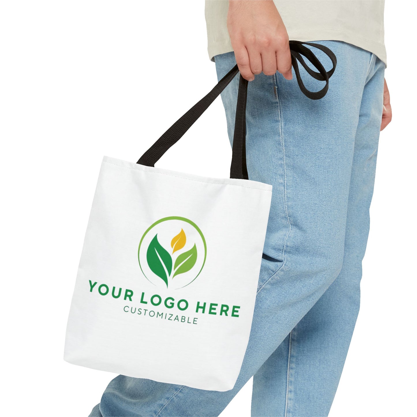 White tote bag with customizable logo held by a person wearing blue jeans.