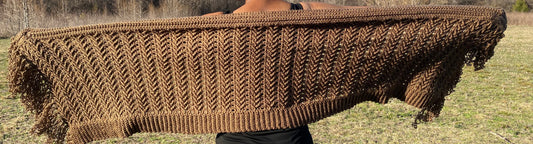 Brown crocheted shawl in a grassy outdoor setting