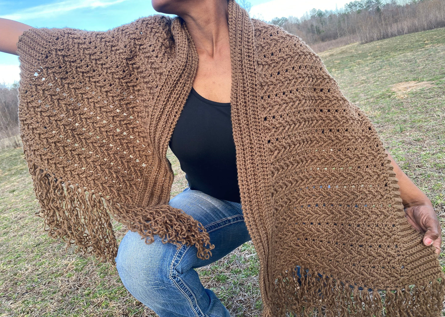 Person wearing a brown crochet shawl in an outdoor setting