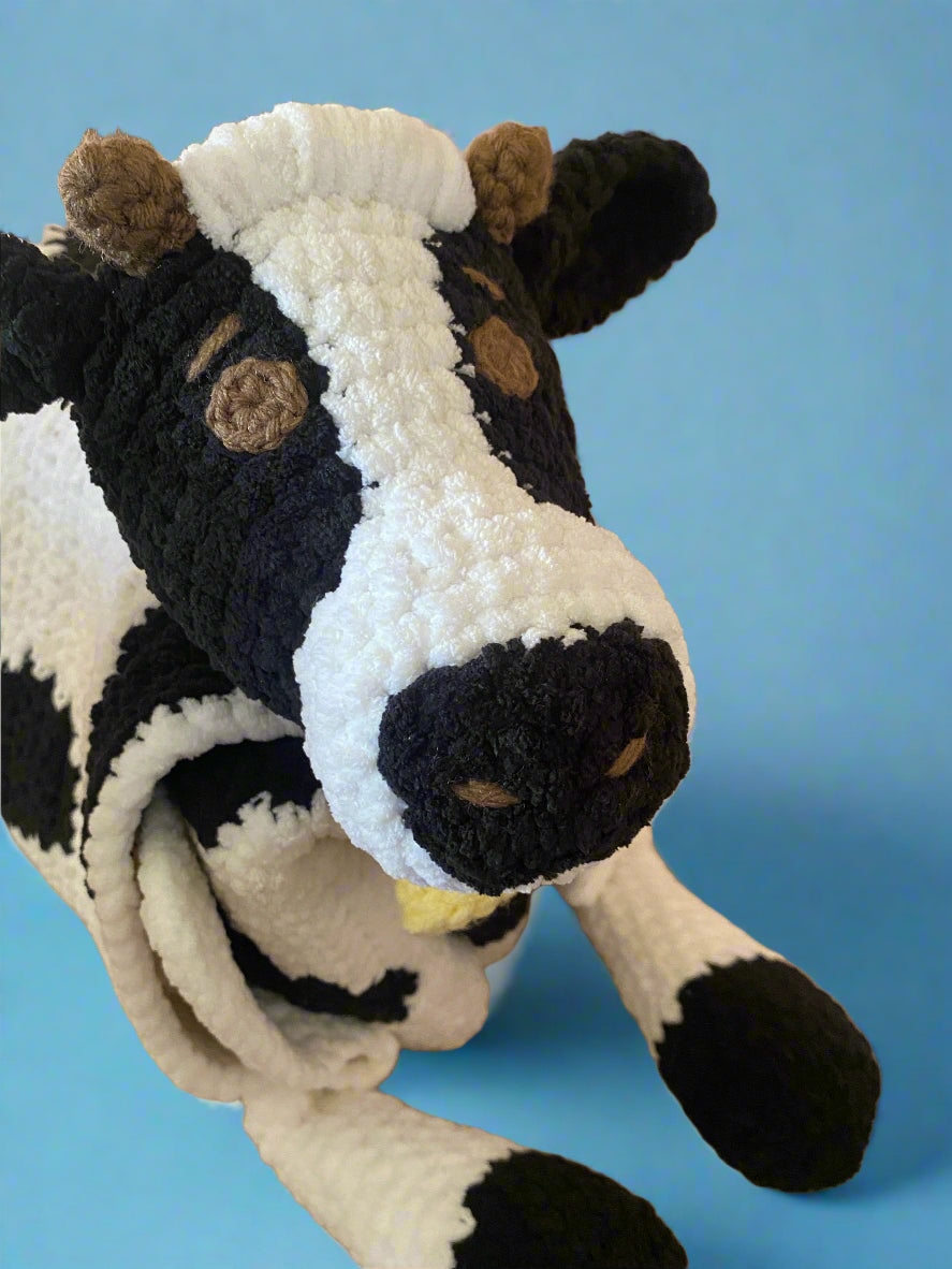 Plush toy cow with black and white pattern on a beige surface