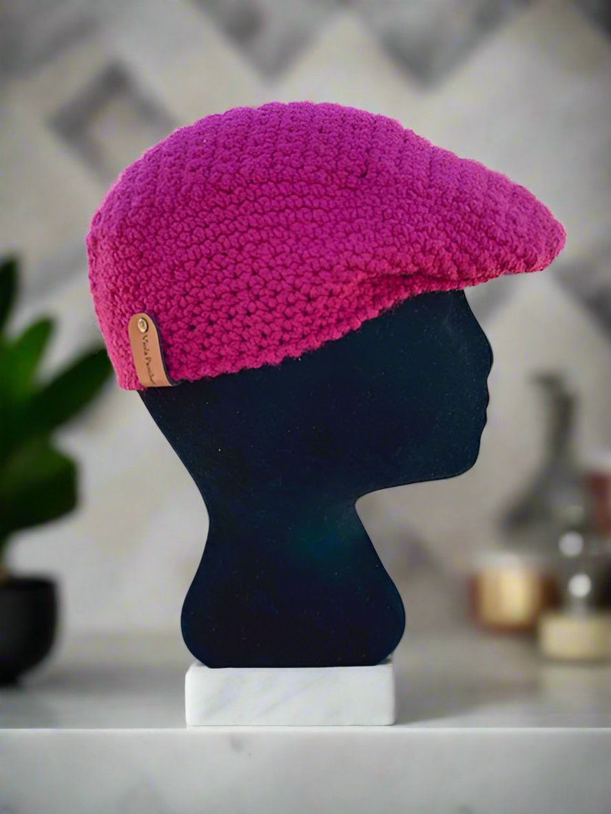 A beige crochet newsboy cap displayed on a mannequin head against a marble background.