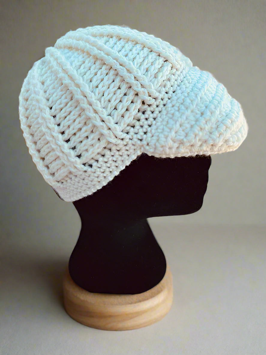 A handcrafted crochet hat in white with a flower design, displayed on a mannequin head, set against a natural background.