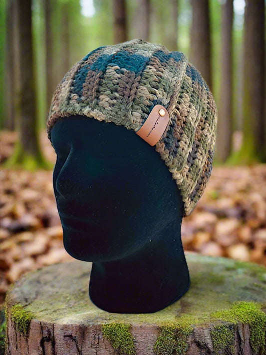 A handmade crochet rimless beanie displayed on a mannequin head, set against a natural outdoor background with trees.