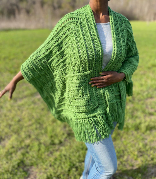 Person wearing a green crocheted poncho in an outdoor setting