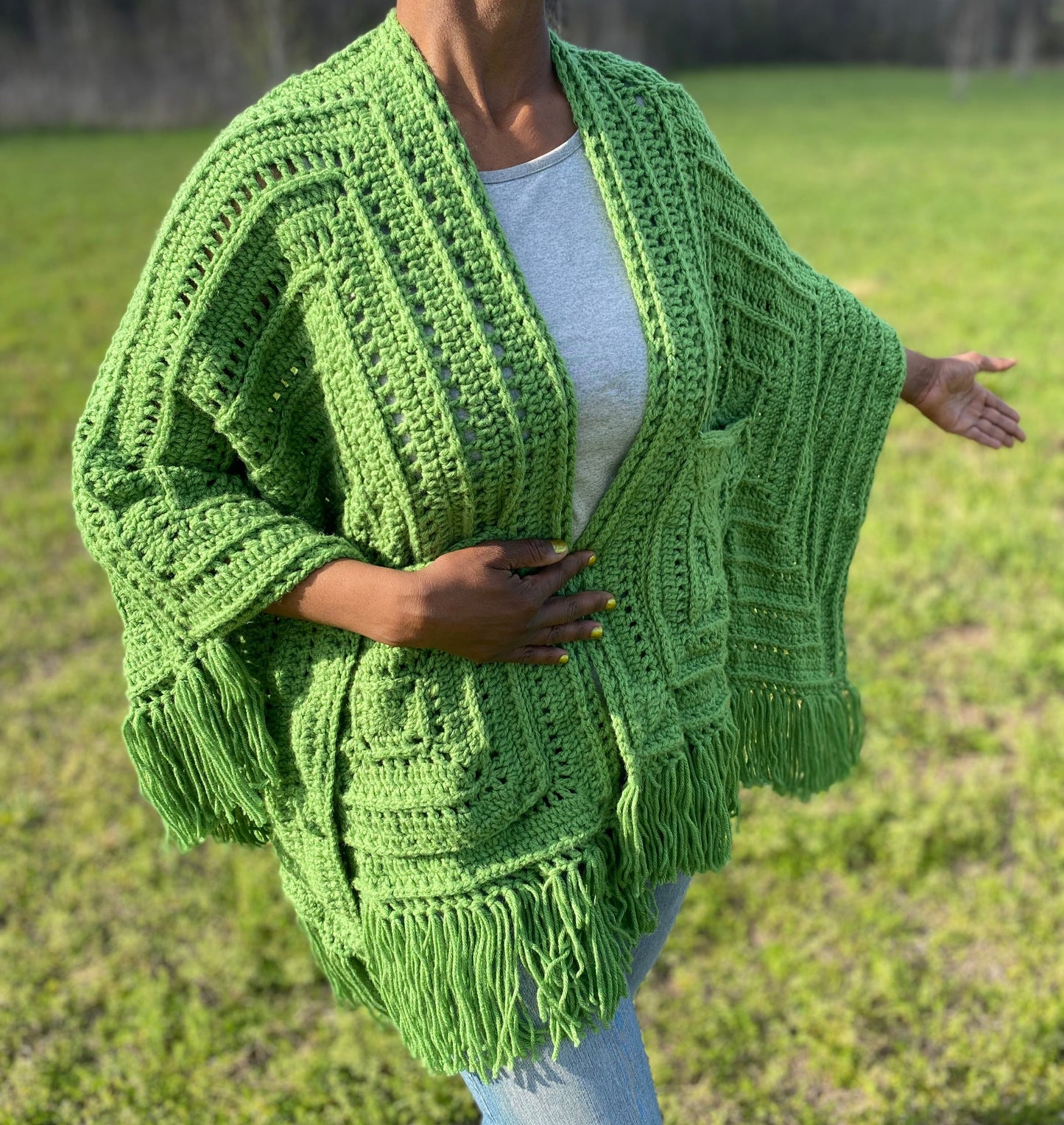 Person wearing a green crochet cardigan in an outdoor setting