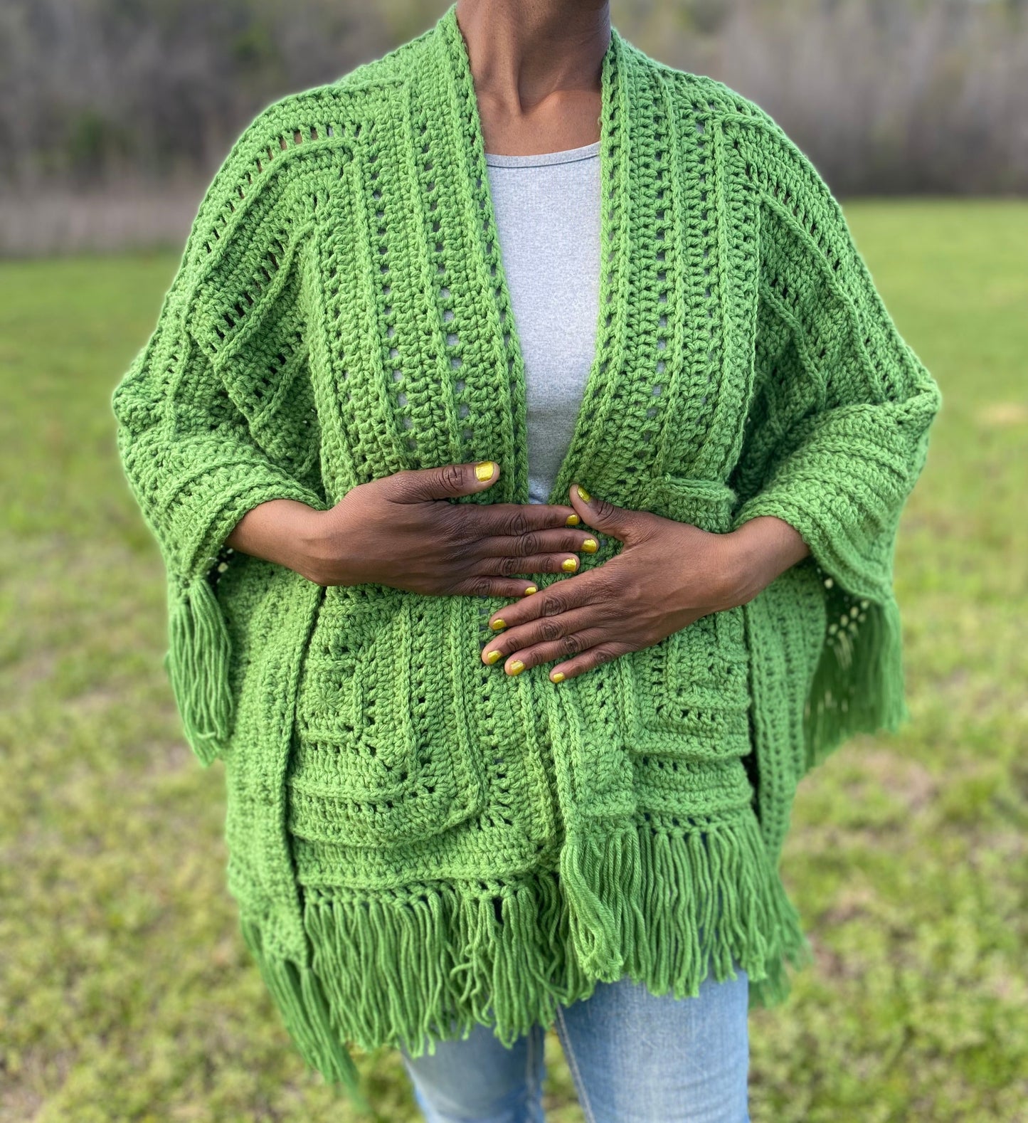 Person wearing a green crochet shawl in an outdoor setting