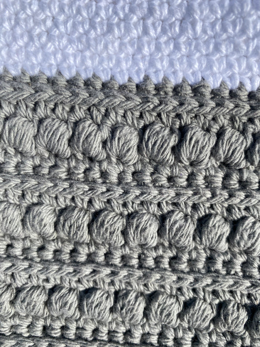 Close-up of a gray yarn with a textured crochet pattern.