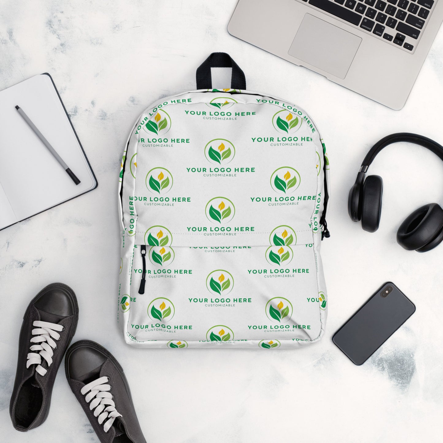 White backpack with green logo pattern on a white surface with accessories.