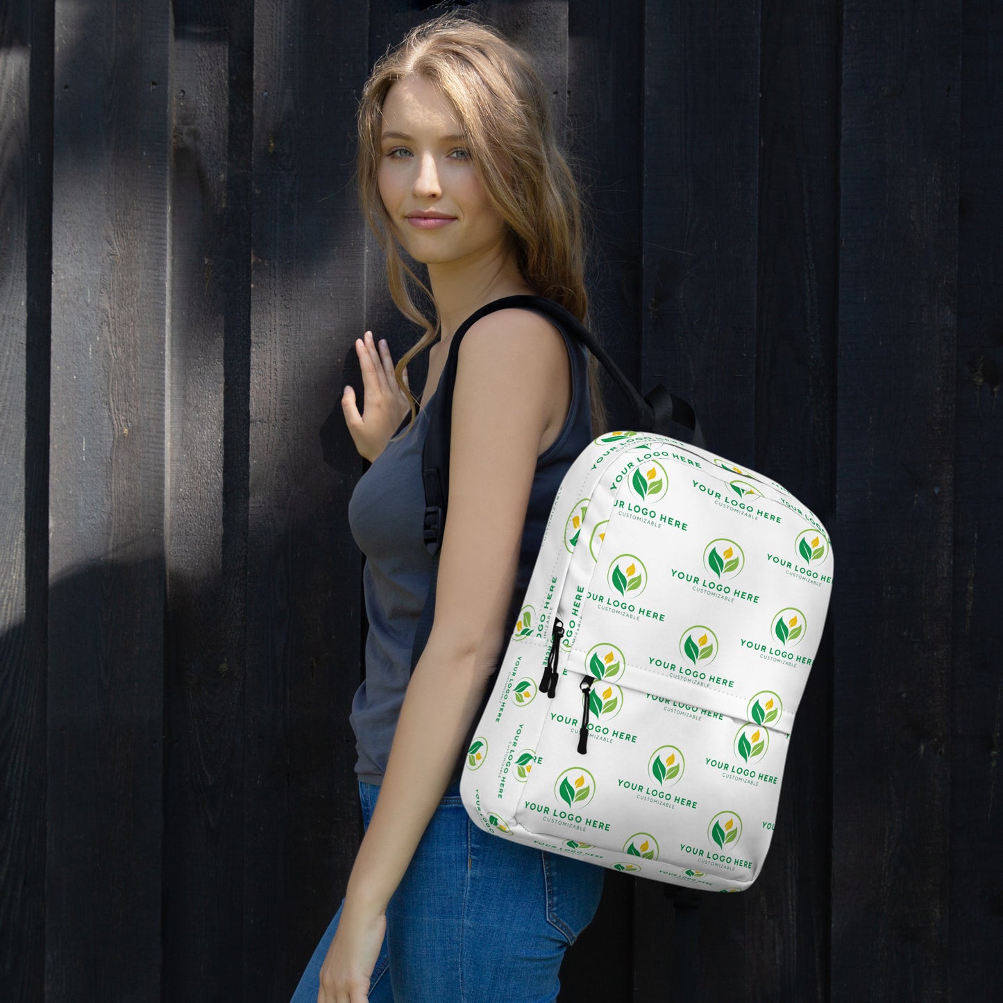 Woman holding a white backpack with green logos against a dark background