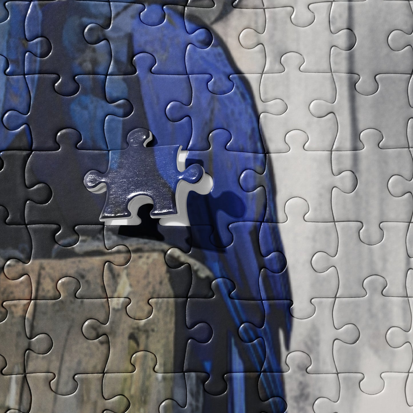 close up of a jigsaw puzzle depicting two blue hyacinth macaws perched on a wooden stump with a custom name label, surrounded by a blurred background.