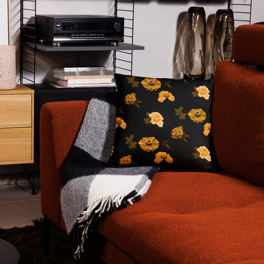 A black cushion with a floral pattern placed on an orange armchair in a cozy living room setting.