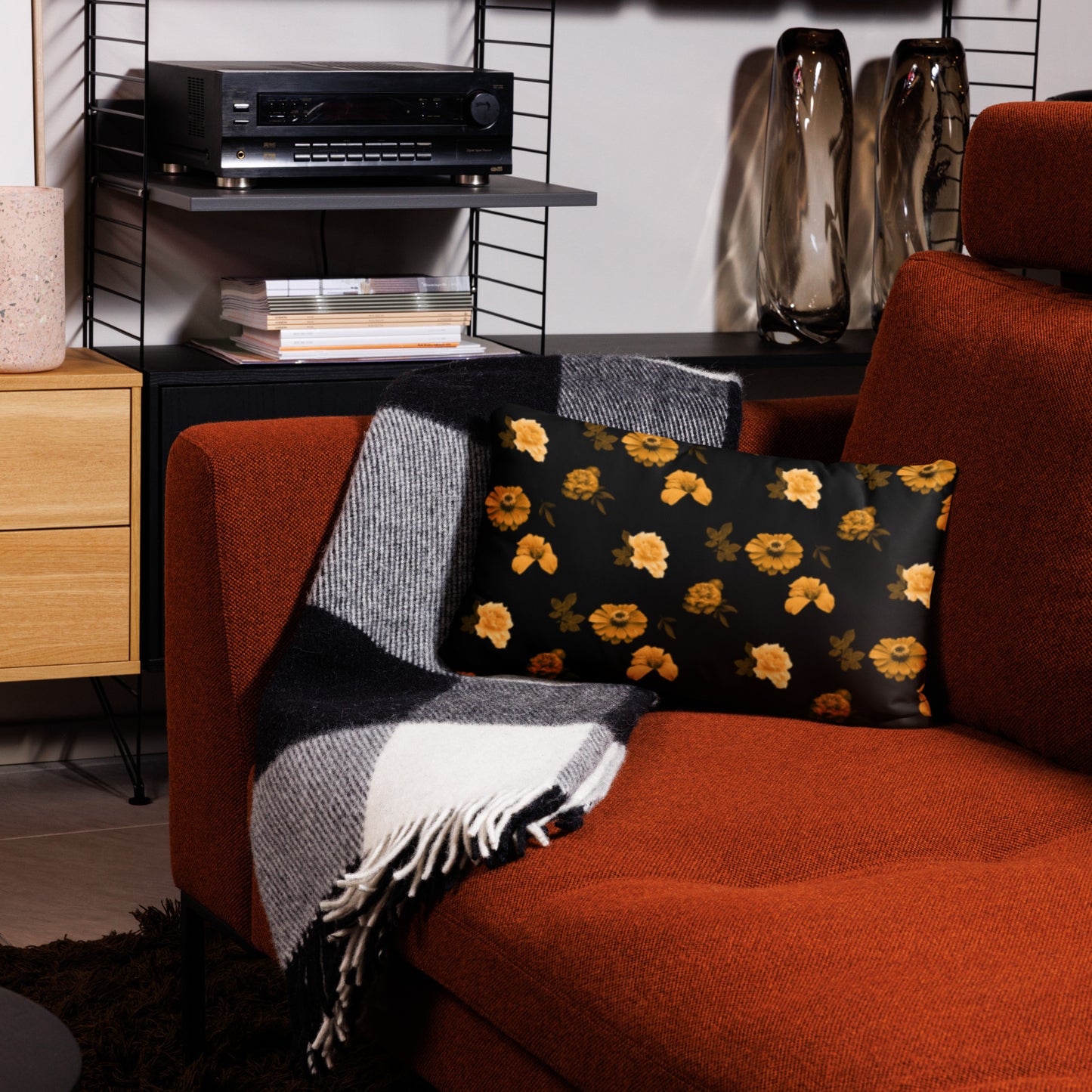 A black cushion with a floral pattern placed on an orange armchair in a cozy living room setting.