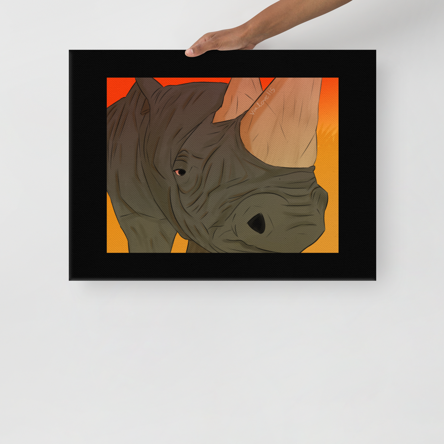 person holding A grayscale canvas print of a white rhino in sharp detail, its massive body and textured skin captured mid-step, symbolizing strength and quiet resilience.
