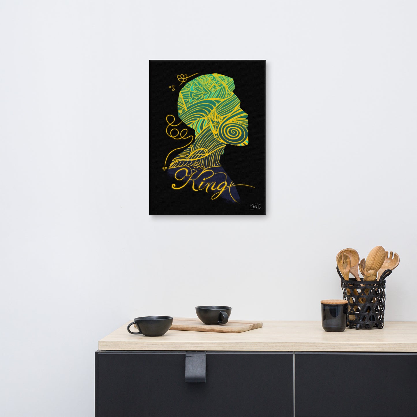 A canvas print titled 'King' displayed on a wall above a kitchen counter, featuring a stylized graphic with yellow and green on a black background.