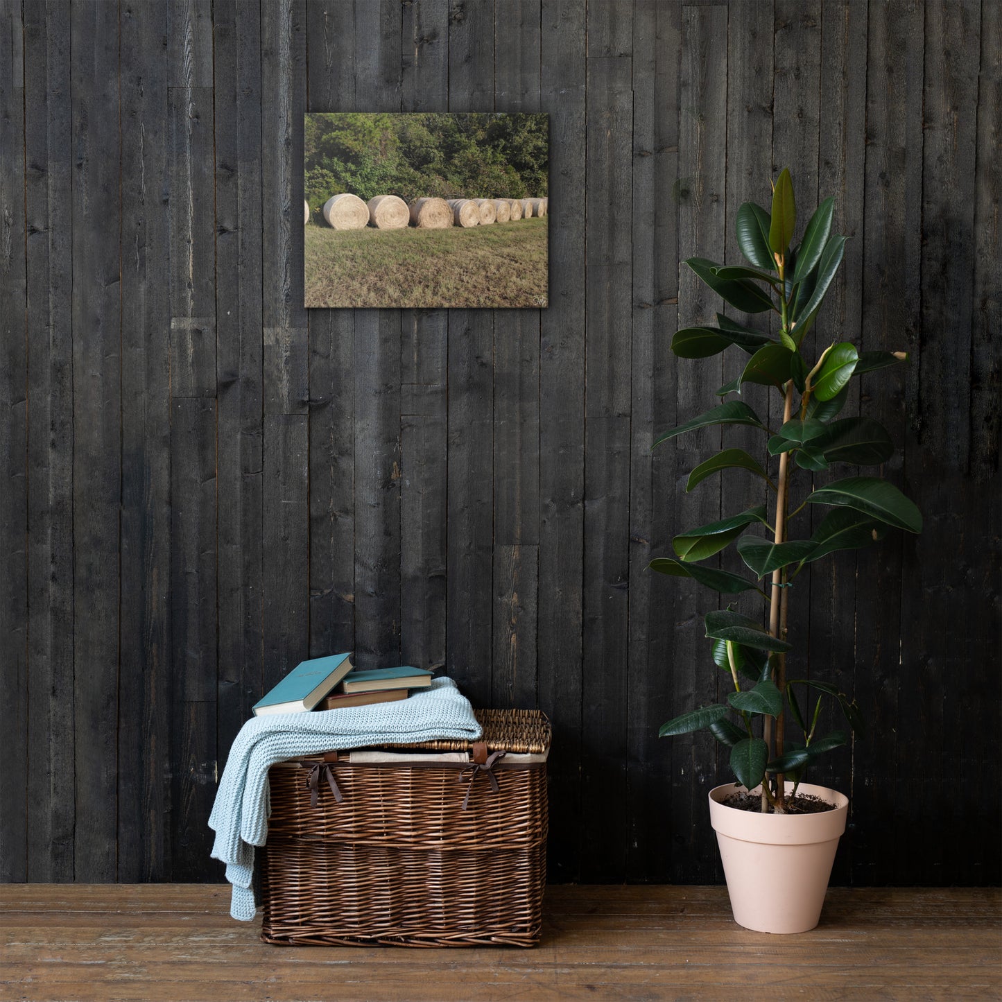 A canvas print featuring a field of hay bales under a clear sky, displayed on a white wall.