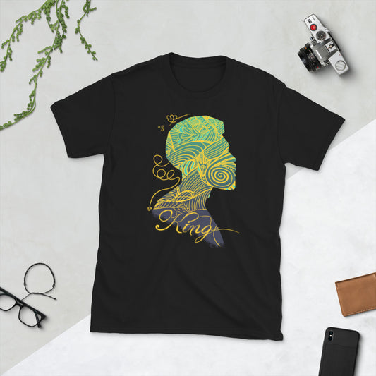A black short-sleeve unisex t-shirt with a printed design of a stylized character's head on the front, surrounded by a variety of items including a camera, glasses, and a phone.
