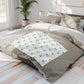 Bedding set with a branded pattern on a bed in a bright bedroom.