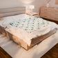 Bed with white bedding featuring avocado patterns in a bedroom setting.