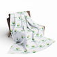 White blanket with green leaf logo and text on a wooden chair against a white background
