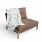 Brown sofa with a white blanket featuring green logos on a white background