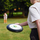 Person holding a frisbee with a logo in a park setting