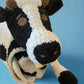 Plush toy cow with black and white pattern on a beige surface