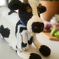 Crocheted cow blanket with black and white pattern on a soft surface