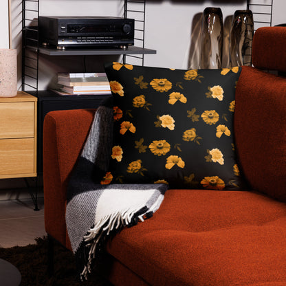 A black cushion with a floral pattern placed on an orange armchair in a cozy living room setting.